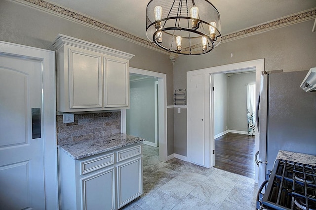 kitchen with light stone counters, ornamental molding, appliances with stainless steel finishes, and a chandelier