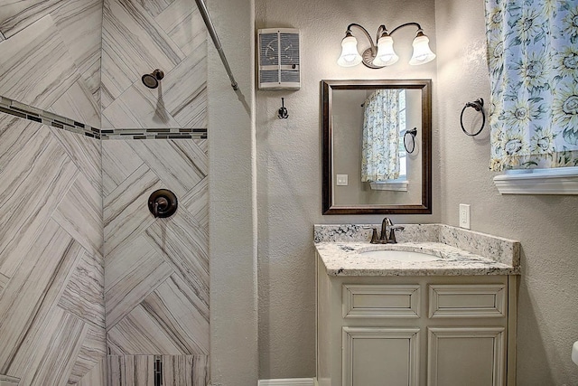 bathroom with a tile shower and vanity