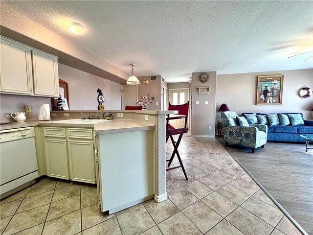15125 Leeward Dr Unit 10, Corpus Christi, TX 78418 - kitchen with white dishwasher, a peninsula, open floor plan, a textured ceiling, and light tile patterned floors