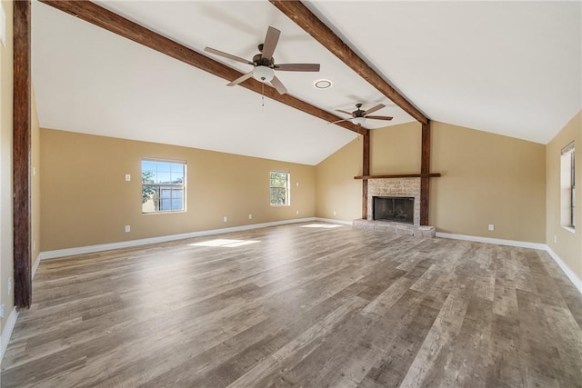 unfurnished living room featuring lofted ceiling with beams, light hardwood / wood-style floors, a fireplace, and ceiling fan