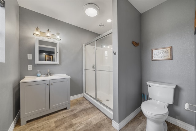 bathroom with hardwood / wood-style flooring, toilet, an enclosed shower, and vanity