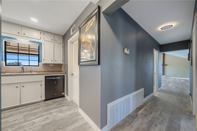 kitchen featuring decorative backsplash, sink, light hardwood / wood-style flooring, dishwasher, and white cabinetry