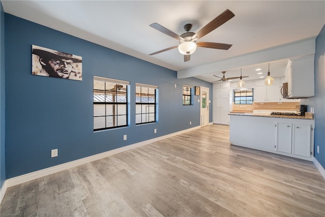 kitchen featuring hanging light fixtures, light hardwood / wood-style flooring, ceiling fan, tasteful backsplash, and white cabinetry