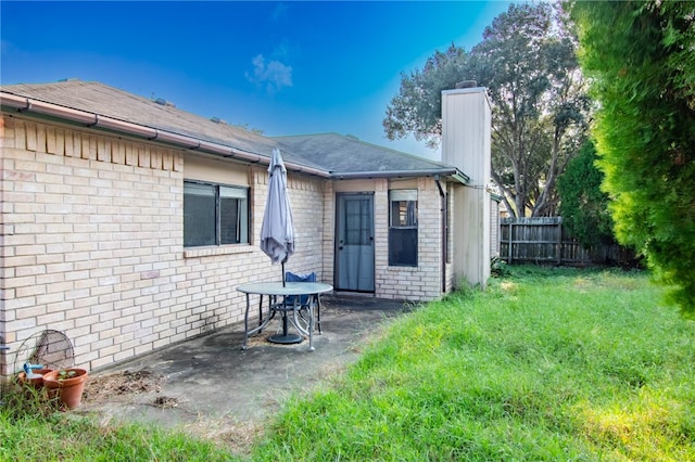 back of property with a yard and a patio