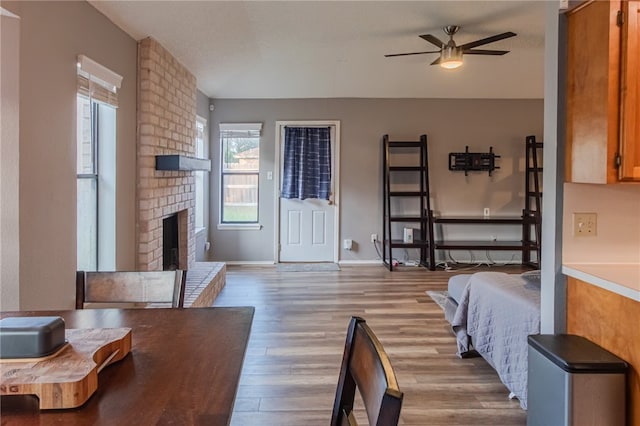 bedroom with ceiling fan, light wood-type flooring, and a fireplace