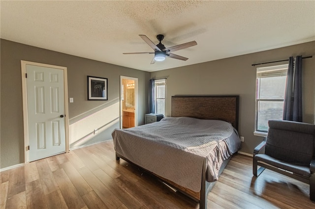 bedroom featuring a textured ceiling, connected bathroom, light hardwood / wood-style flooring, and ceiling fan