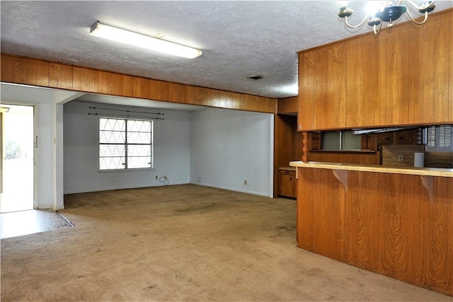 kitchen featuring light carpet, a peninsula, brown cabinets, and light countertops