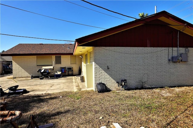 view of property exterior featuring a patio area and brick siding