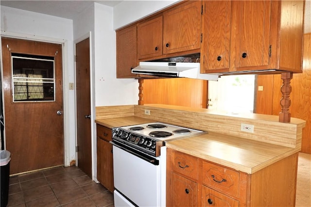 kitchen featuring white electric stove, brown cabinetry, dark tile patterned flooring, light countertops, and under cabinet range hood