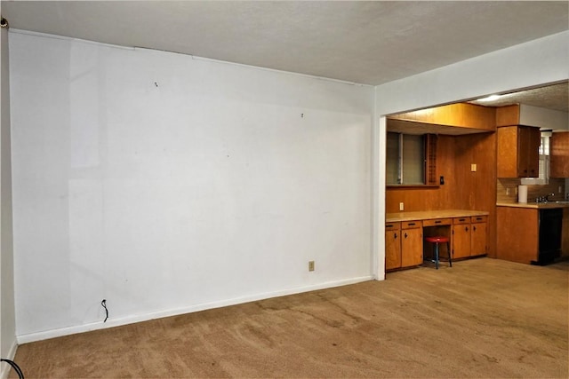 kitchen with brown cabinetry, baseboards, light countertops, and light colored carpet