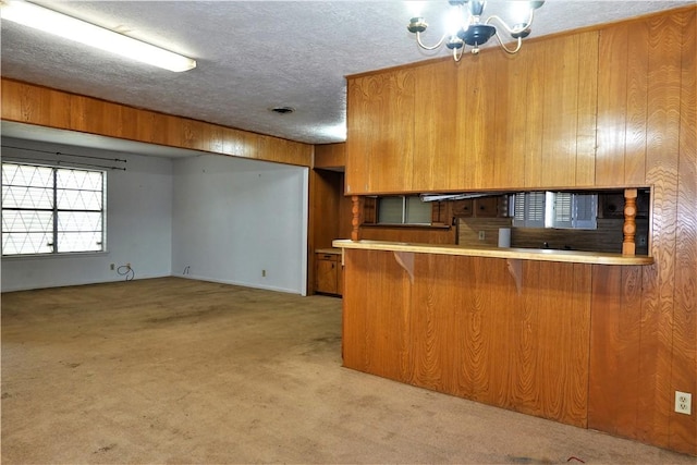 kitchen featuring brown cabinets, light countertops, light carpet, and a peninsula