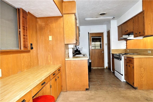 kitchen with brown cabinetry, white gas range, under cabinet range hood, and light countertops