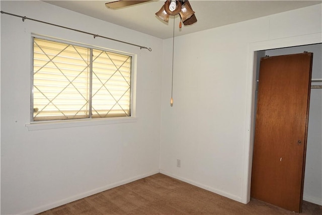 carpeted empty room with ceiling fan and baseboards