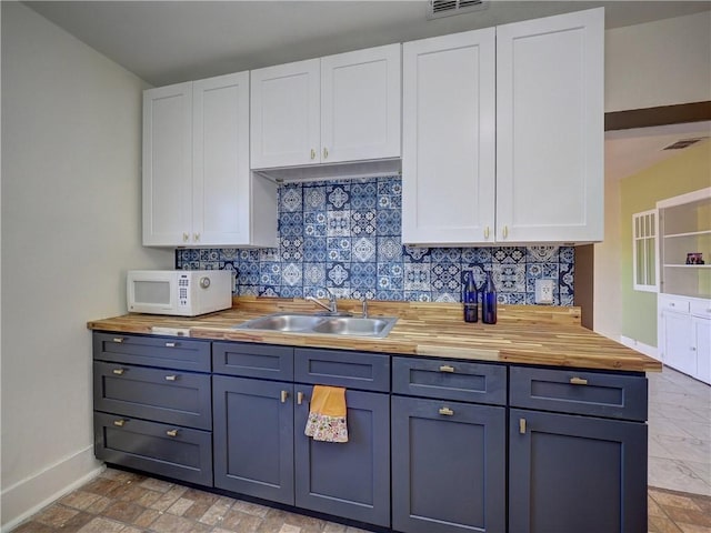 kitchen featuring tasteful backsplash, sink, white cabinets, and wooden counters