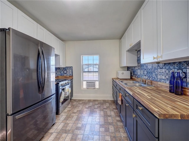 kitchen featuring white cabinets, stainless steel appliances, butcher block countertops, and sink