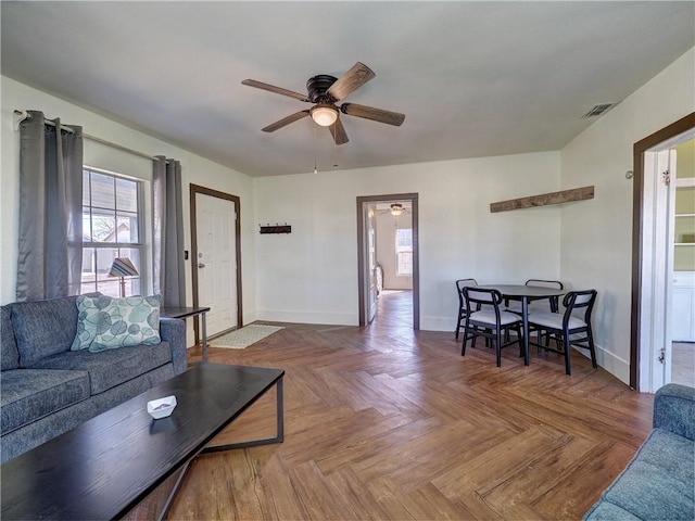 living room featuring ceiling fan, plenty of natural light, and parquet flooring