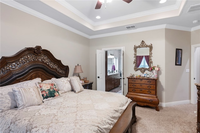 bedroom featuring ornamental molding, ensuite bathroom, ceiling fan, a tray ceiling, and carpet