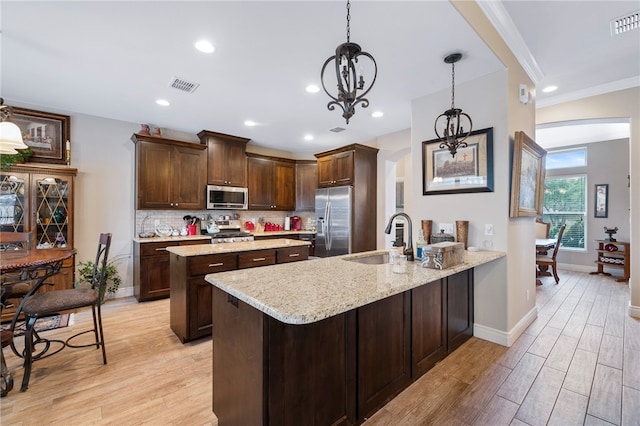 kitchen featuring kitchen peninsula, a notable chandelier, sink, pendant lighting, and appliances with stainless steel finishes