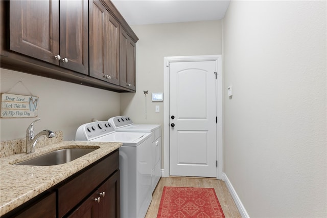 laundry area with cabinets, light hardwood / wood-style flooring, sink, and independent washer and dryer