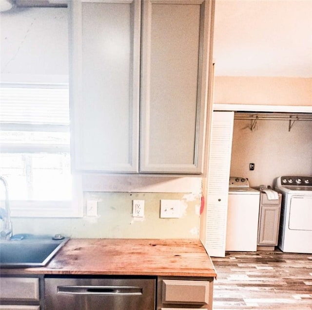 kitchen with dishwasher, light wood-type flooring, washer and clothes dryer, and sink