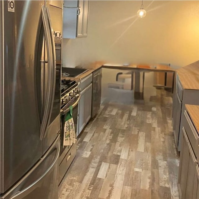 kitchen featuring butcher block counters, gray cabinetry, appliances with stainless steel finishes, and hardwood / wood-style floors