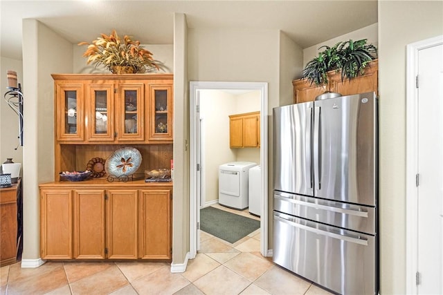 kitchen featuring light tile patterned flooring, brown cabinetry, glass insert cabinets, and freestanding refrigerator