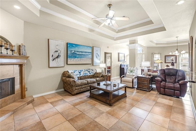 living area featuring light tile patterned floors, a tiled fireplace, a raised ceiling, and crown molding