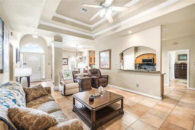 living area with light tile patterned floors, a ceiling fan, visible vents, a tray ceiling, and ornate columns