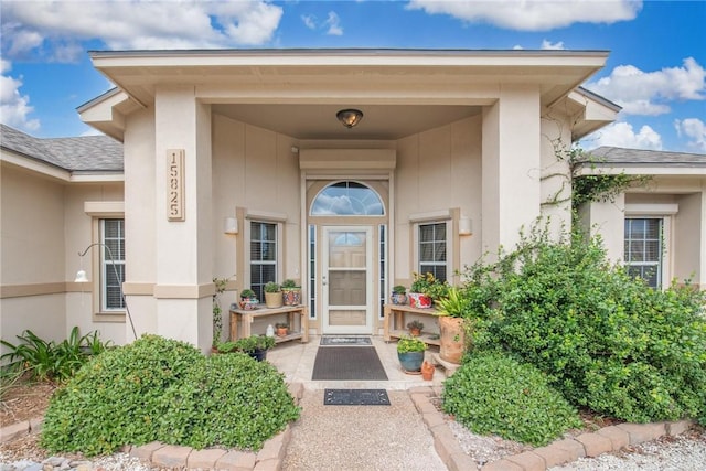 property entrance with a shingled roof and stucco siding