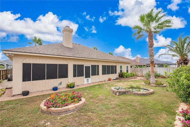 back of property featuring roof with shingles, a chimney, fence, and a yard