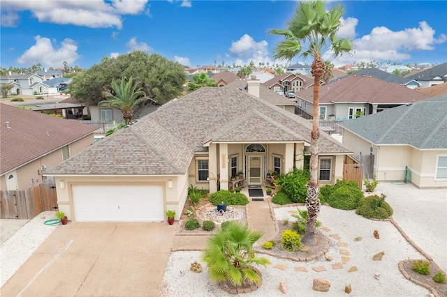 view of front facade featuring concrete driveway, fence, a residential view, and stucco siding