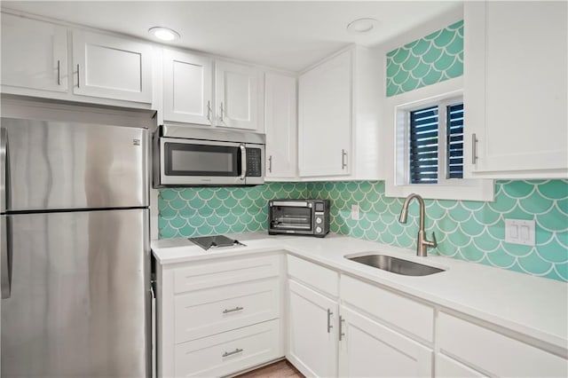 kitchen featuring a sink, white cabinetry, light countertops, appliances with stainless steel finishes, and tasteful backsplash