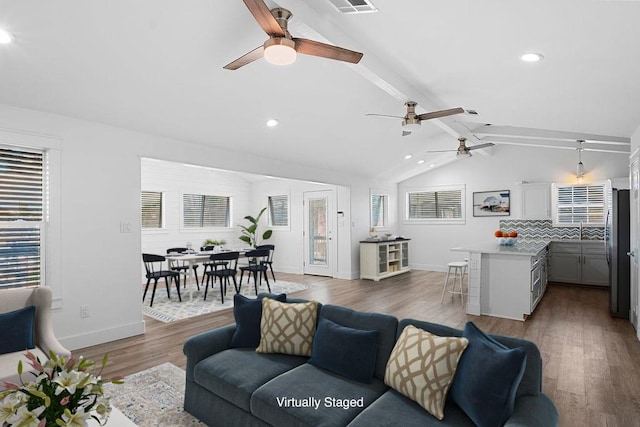 living room with vaulted ceiling with beams, recessed lighting, wood finished floors, and baseboards