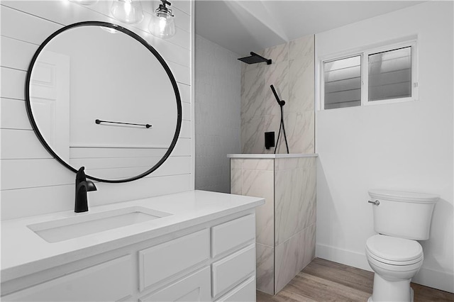 bathroom with toilet, vanity, wood finished floors, baseboards, and a walk in shower