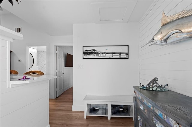 hallway featuring wood walls, visible vents, and wood finished floors