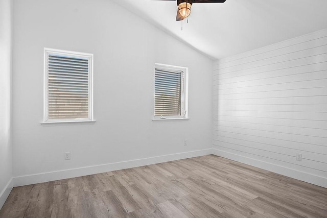 empty room with lofted ceiling, wood finished floors, a ceiling fan, and baseboards