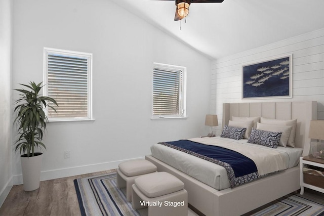 bedroom with lofted ceiling, multiple windows, baseboards, and wood finished floors