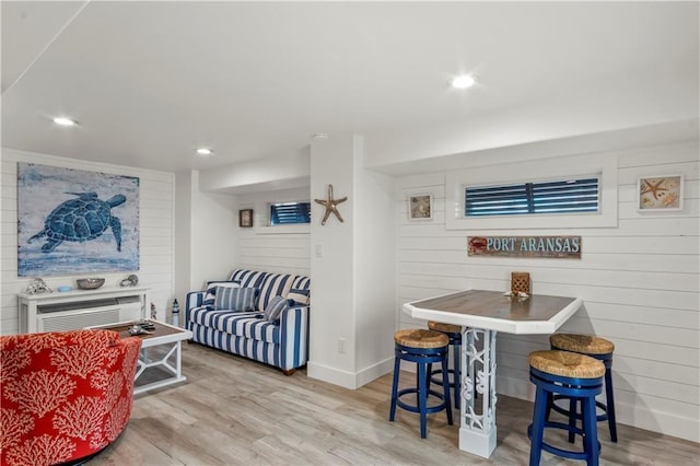 living area with recessed lighting, wooden walls, baseboards, and wood finished floors