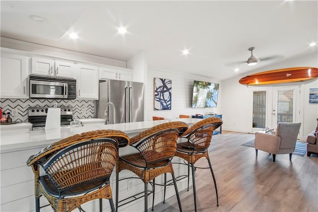 kitchen with appliances with stainless steel finishes, light wood-type flooring, decorative backsplash, and white cabinets