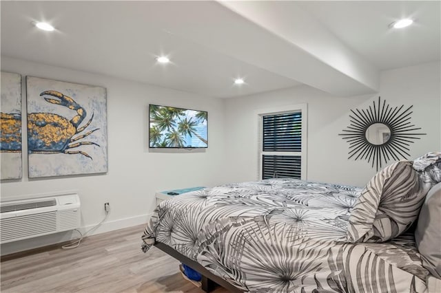 bedroom with a wall unit AC, baseboards, wood finished floors, and recessed lighting