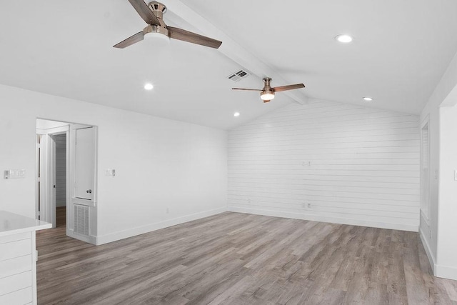 empty room with vaulted ceiling with beams, light wood-type flooring, visible vents, and baseboards