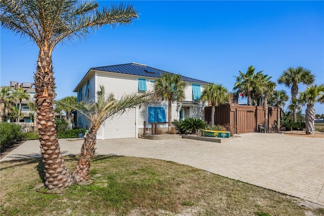 view of front of home featuring driveway, metal roof, a standing seam roof, fence, and stucco siding