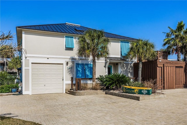 view of front of home with a garage, metal roof, a standing seam roof, fence, and decorative driveway