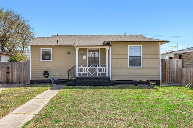 bungalow-style home with a front yard and fence