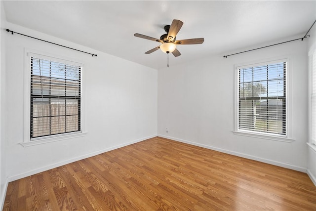 unfurnished room with light wood-type flooring, a ceiling fan, and baseboards