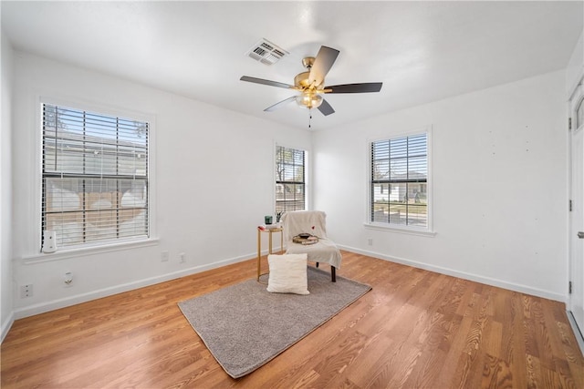 sitting room with ceiling fan, light wood finished floors, visible vents, and baseboards