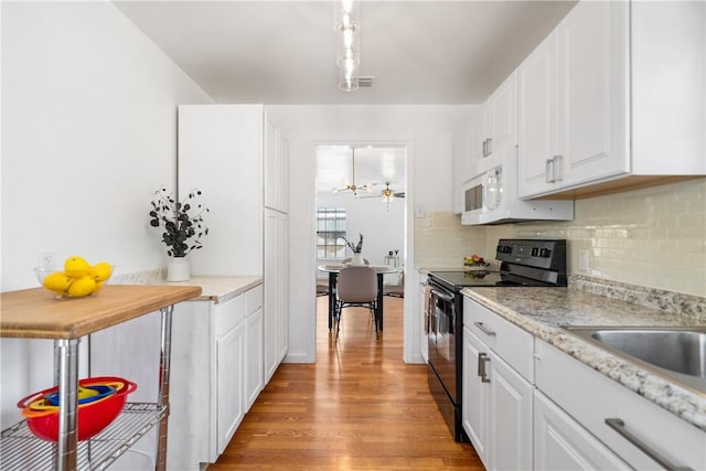 kitchen featuring black range with electric cooktop, white cabinets, light countertops, decorative backsplash, and light wood finished floors