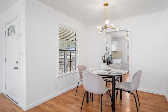 dining space with a chandelier, light wood-type flooring, and baseboards