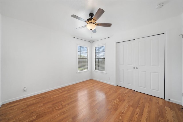 unfurnished bedroom featuring a closet, ceiling fan, baseboards, and wood finished floors