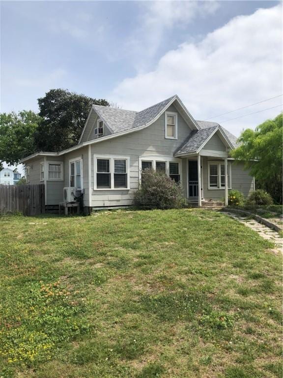 view of front of home with fence, a shingled roof, and a front lawn